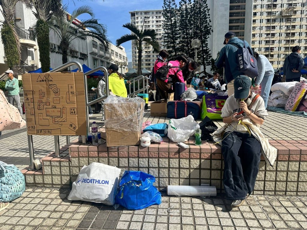 Volunteer Jay (in a blue cap) sits next to a cardboard map of the area. Photo: Natalie Wong