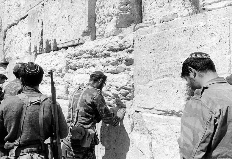 Pulpit to Pentagon: the evangelicals who see Iran war as Gods plan 117 A black and white photo shows the backs of three men in military uniforms facing a wall of large, rough stone blocks.