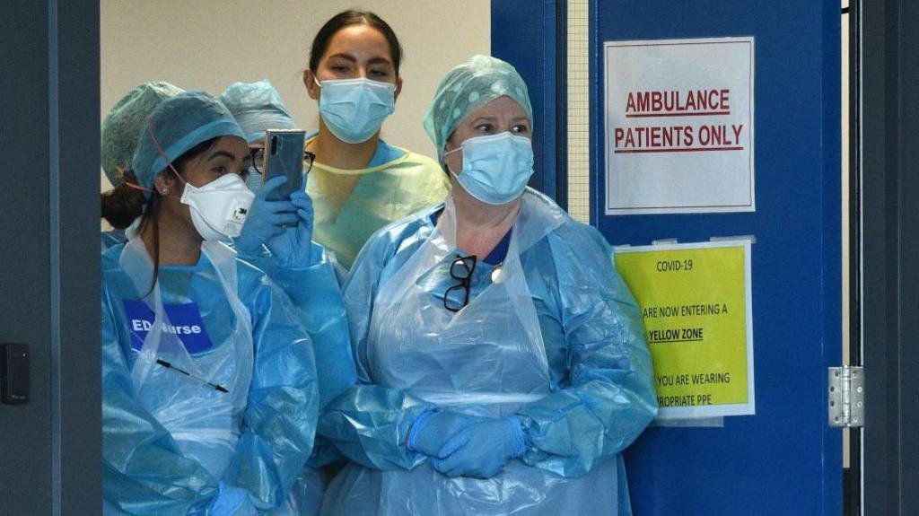 PPE failures left NHS staff poorly protected and wasted £10bn, Covid inquiry finds 26 Four medics are standing at the doors of an emergency department in the pandemic. They are wearing plastic blue gowns and have face masks on. One has a sign on her chest saying "ED Nurse".